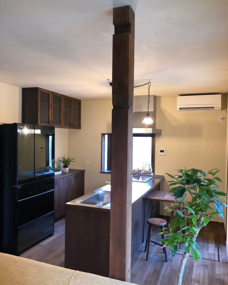 木の風合いを活かしたブリティッシュスタイルのキッチンと観葉植物のある室内（加藤住建）