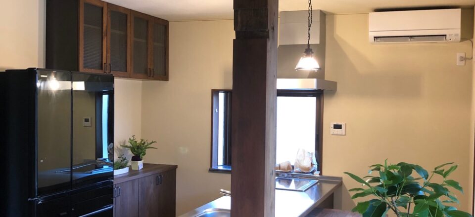木の風合いを活かしたブリティッシュスタイルのキッチンと観葉植物のある室内（加藤住建）