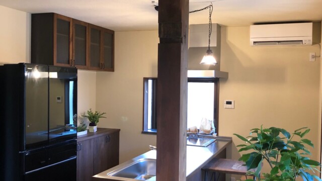 木の風合いを活かしたブリティッシュスタイルのキッチンと観葉植物のある室内（加藤住建）